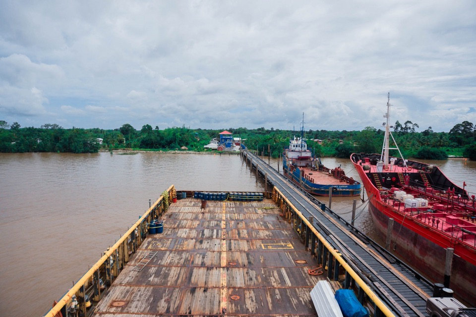 A GCITI cargo barge loaded at the wharf at Parika, with vessels alongside on the Essequibo river.