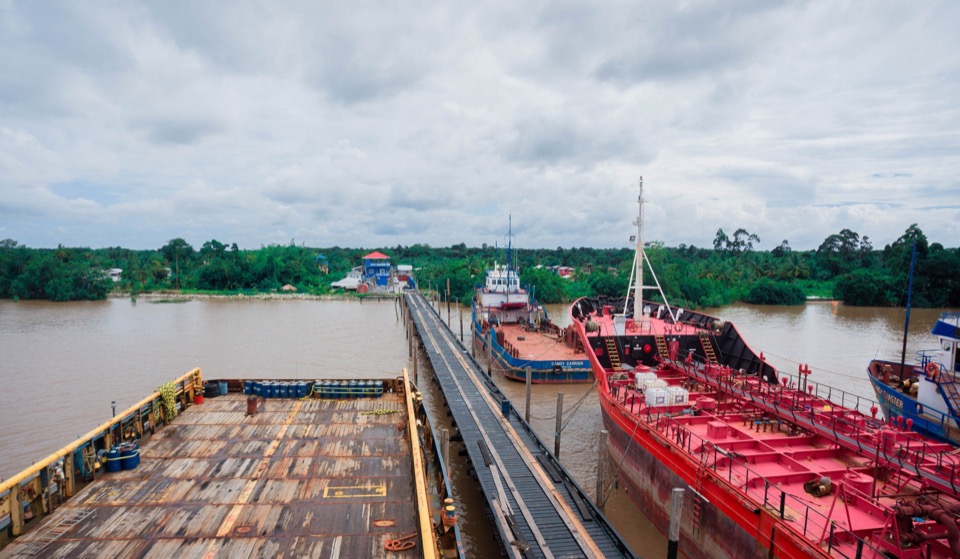 GCITI's wharf at Parika on the Essequibo river: a cargo barge in the foreground, Candy Carrier alongside, and the timber jetty running to the forested riverbank.